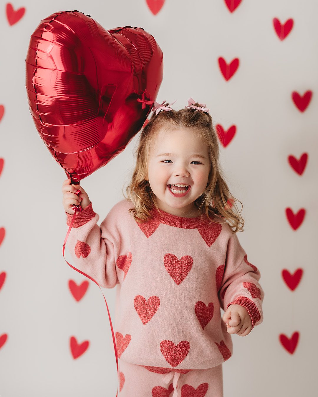 Little girl smiling and holding a red heart balloon during Valentine’s Mini Session at Shannon Payne Photography’s Hendersonville studio.