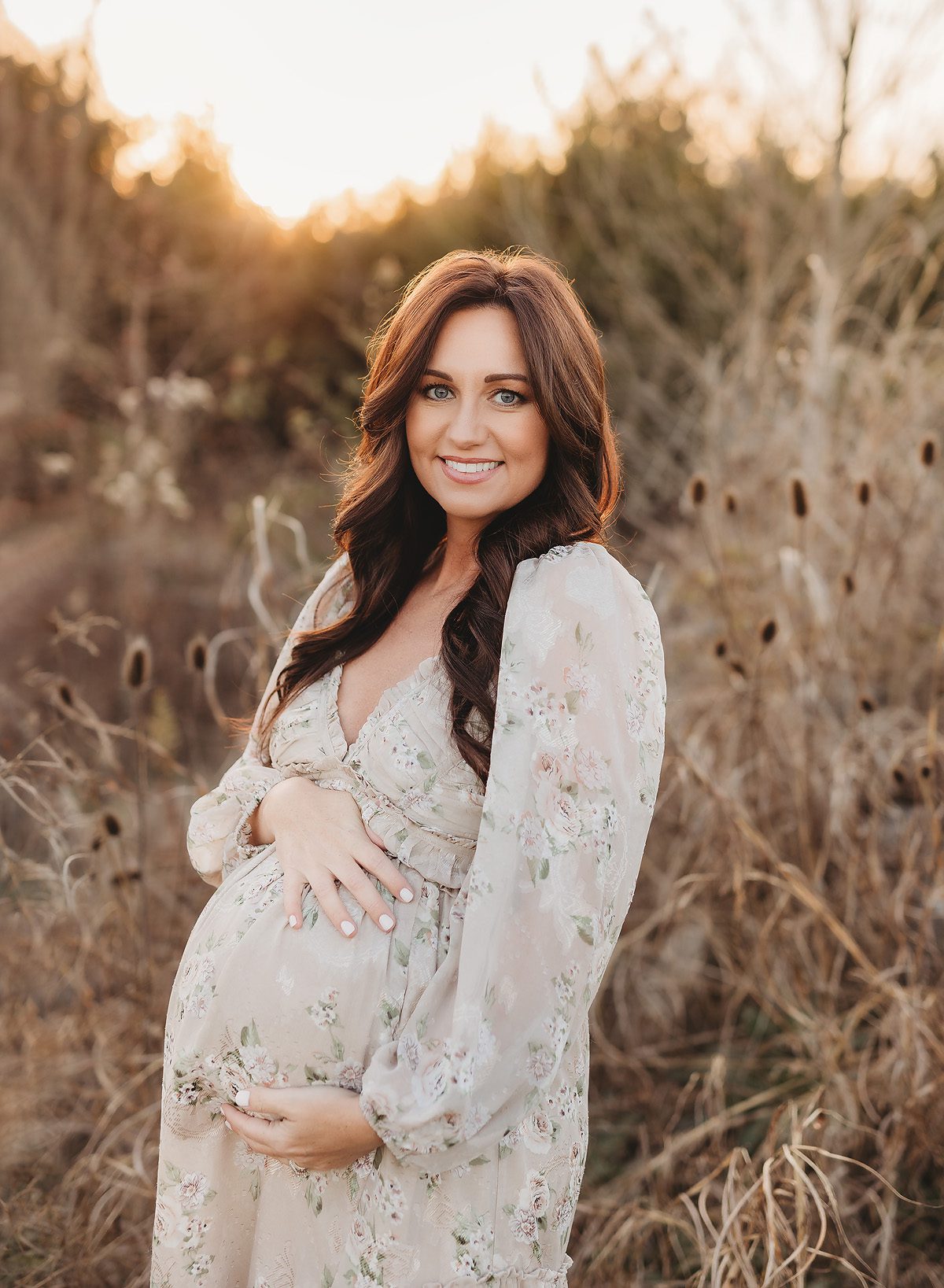 expecting mom holding belly in field during golden hour maternity photos in Nashville